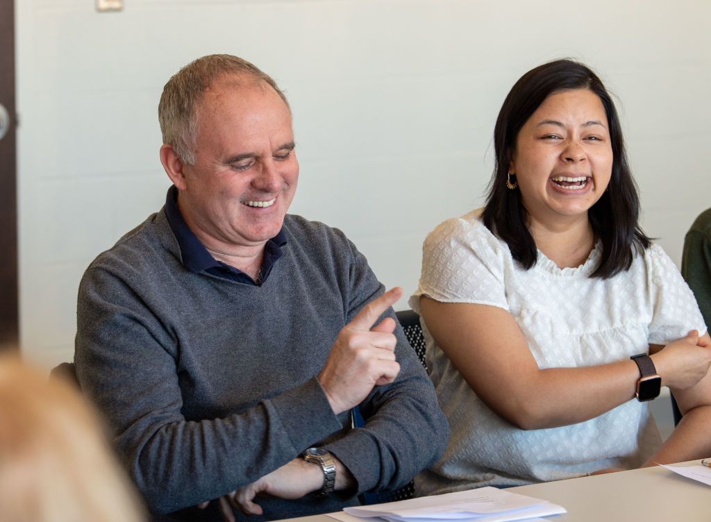 two people, male and female smiling and gesturing at a table