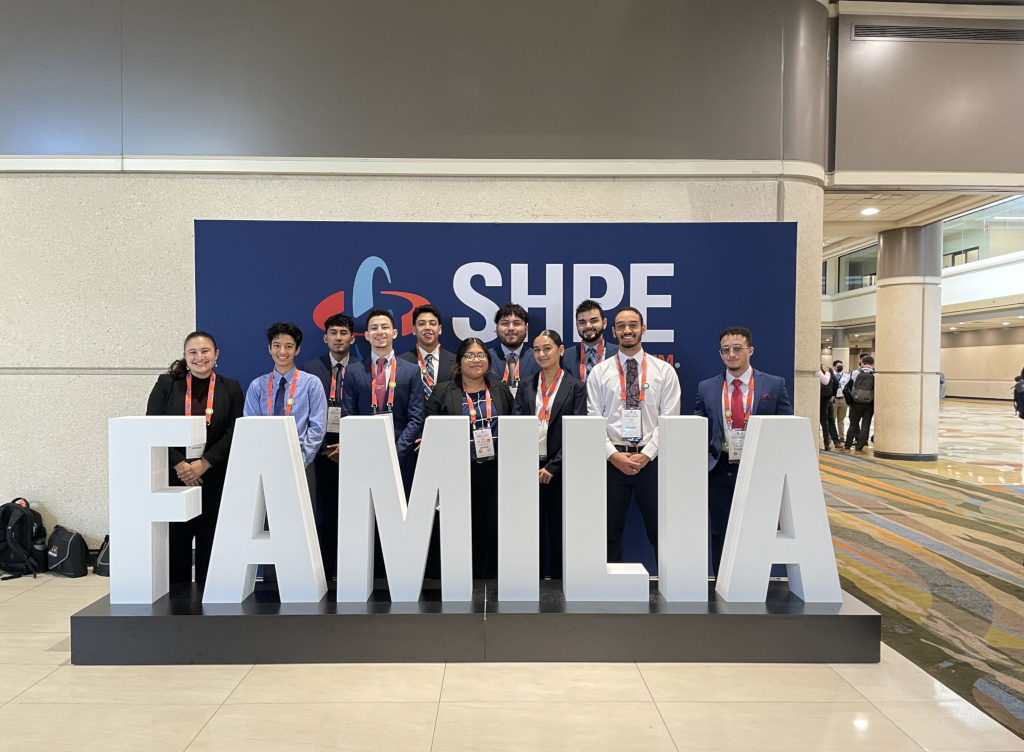 Society of Hispanic Professional Engineers members in front of a familia letters