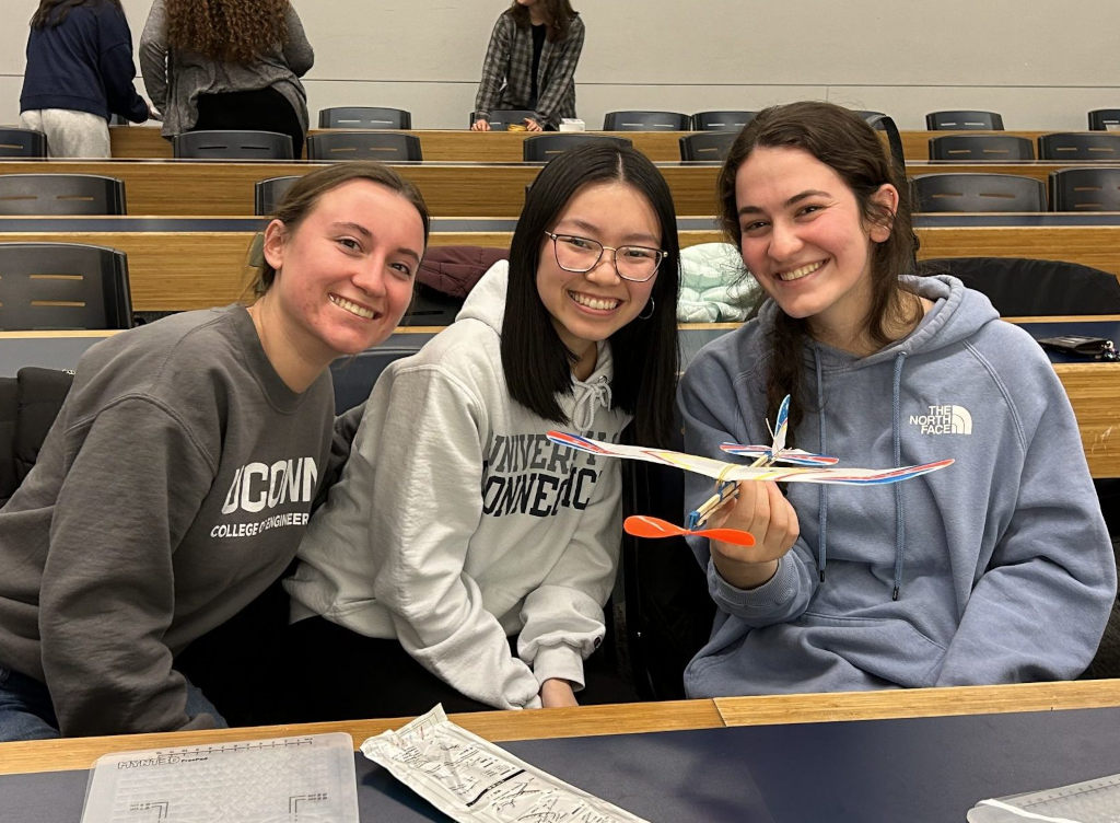 three Society of Women Engineers female members holding a airplane