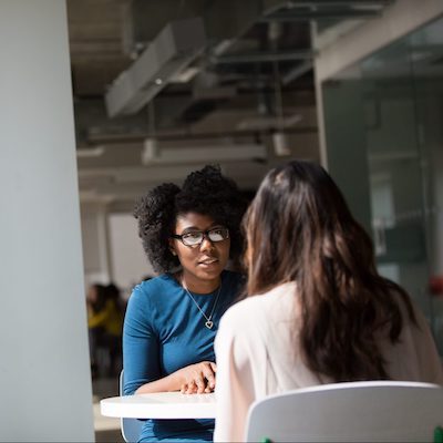 two female peers at a table discussing different topics