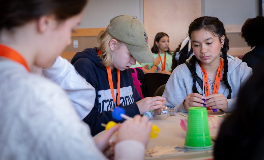 A photo taken at the Multiply Your Options event in the Student Union Ballroom of 8th graders using plastic bottles and cups to do a scientific actvity.