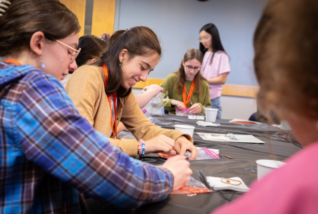A photo taken at the Multiply Your Options event in the Student Union Ballroom of 8th graders and UConn volunteers focusing on completing a scientific actvity.