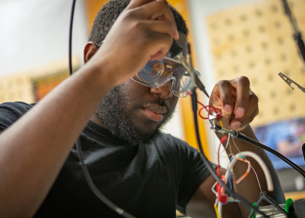 A student concentrating while sodering wires togther.