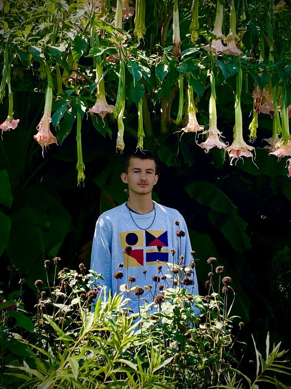 A photo of Ben taken in a area filled with green and pink plants.