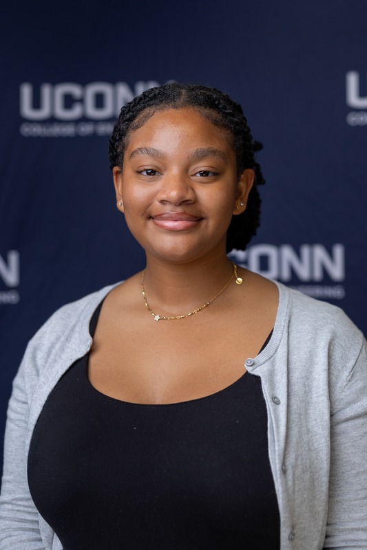 A professional portrait of Kelsey taken in front of a blue and white UConn College of Engineering backdrop.